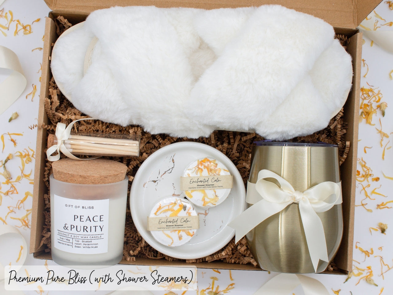 Luxury gift box for her. Featuring a stainless steel tumbler, an aromatherapy candle with matches, aromatic shower steamers, sleek ceramic dish, and plush open-toe slippers. All items are beautifully arranged for a pampering experience.
