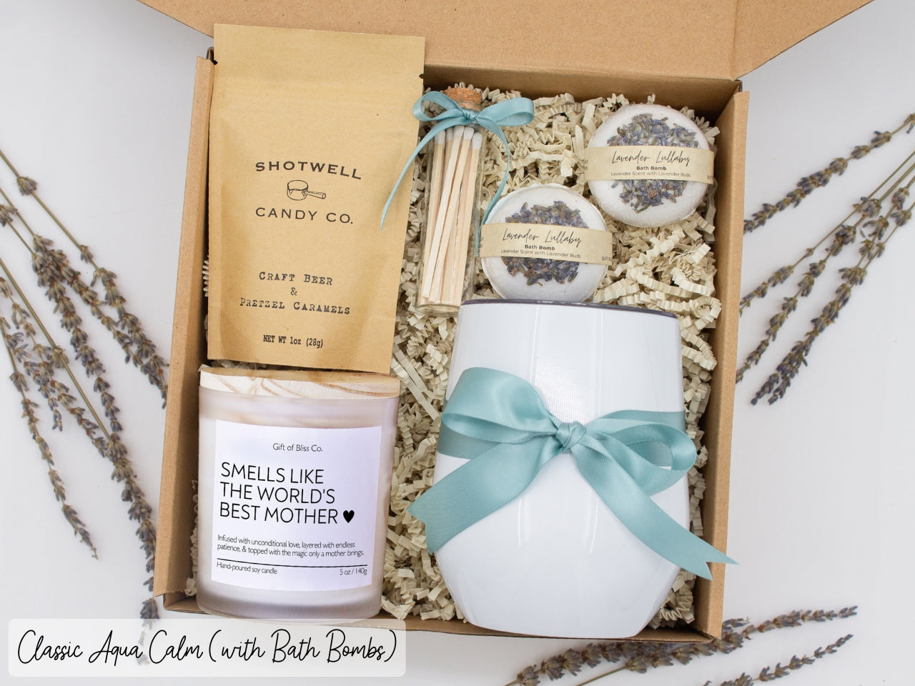 Luxury gift box for mom. Featuring a stainless steel tumbler, an aromatherapy candle with mom-themed label and charming match jar, luxury bath bombs, and gourmet caramel treats. All items are beautifully arranged for a pampering experience.