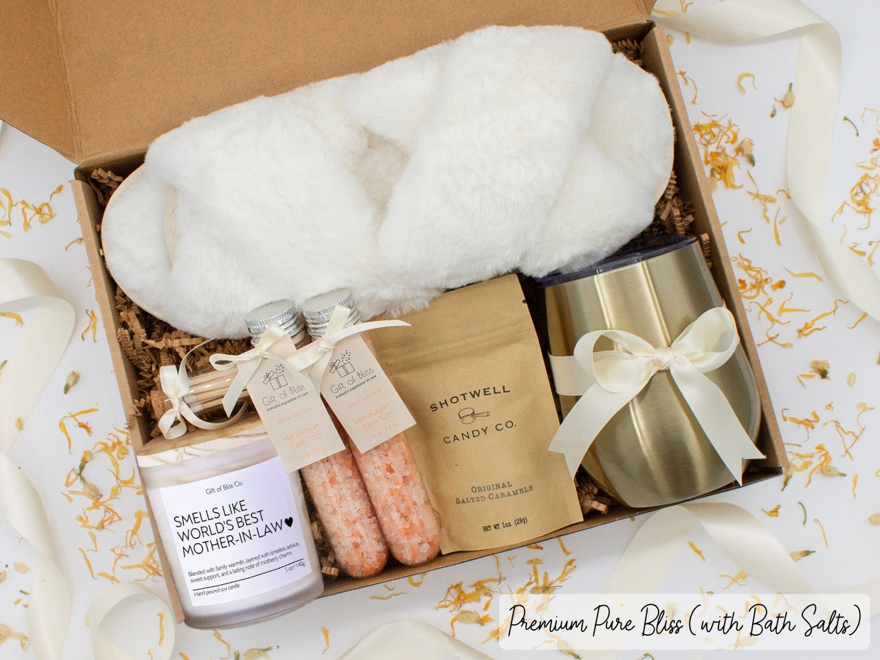 Luxury gift box for her. Featuring a stainless steel tumbler, an aromatherapy candle with mom-themed label and a charming match jar, therapeutic bath salts, plush open-toe slippers, and gourmet caramel treats. All items are beautifully arranged for a pampering experience.