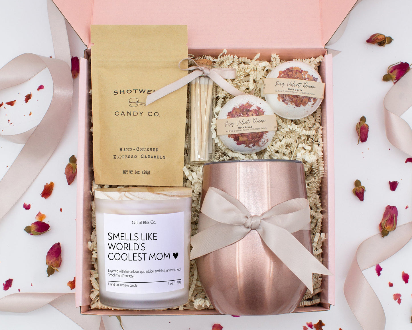 A luxury spa gift box for mom featuring a stainless steel tumbler, an aromatherapy candle with matches, therapeutic bath bombs, and gourmet caramel treats. All items are beautifully arranged for a pampering experience.