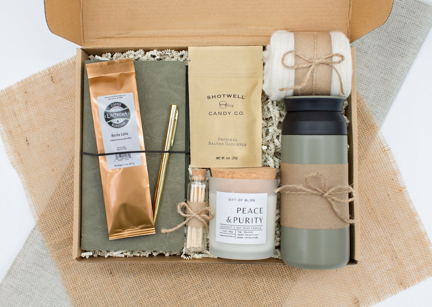A specially crafted gift box for those who appreciate rustic charm and elegance. Features 12 oz tumbler, coffee, luxurious caramel, notebook with gold pen, soothing candle with matches, and cozy socks, perfect for both relaxation and practicality.