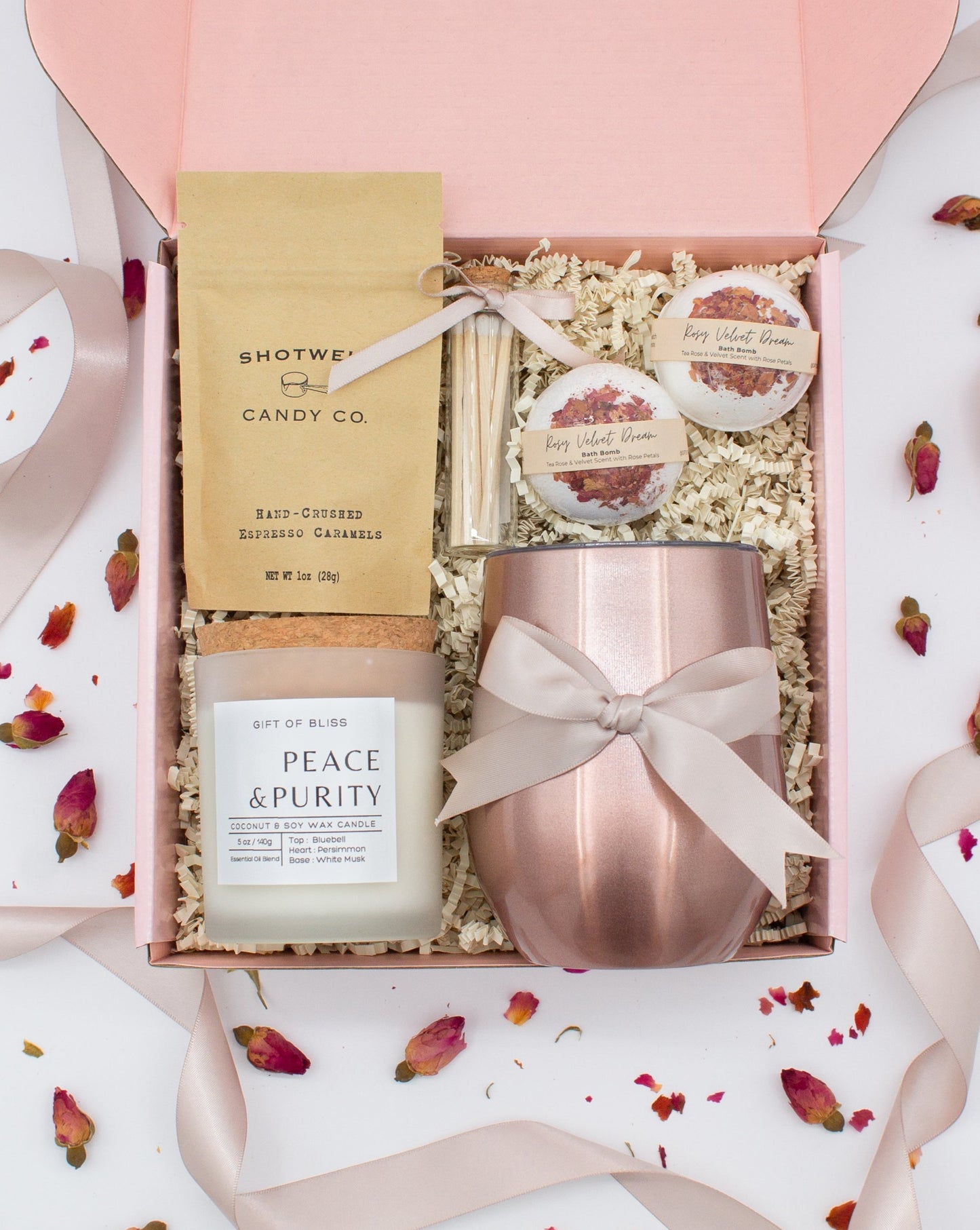 Luxury gift box for her. Featuring a stainless steel tumbler, an aromatherapy candle with matches, luxury bath bombs, and gourmet caramel treats. All items are beautifully arranged for a pampering experience.