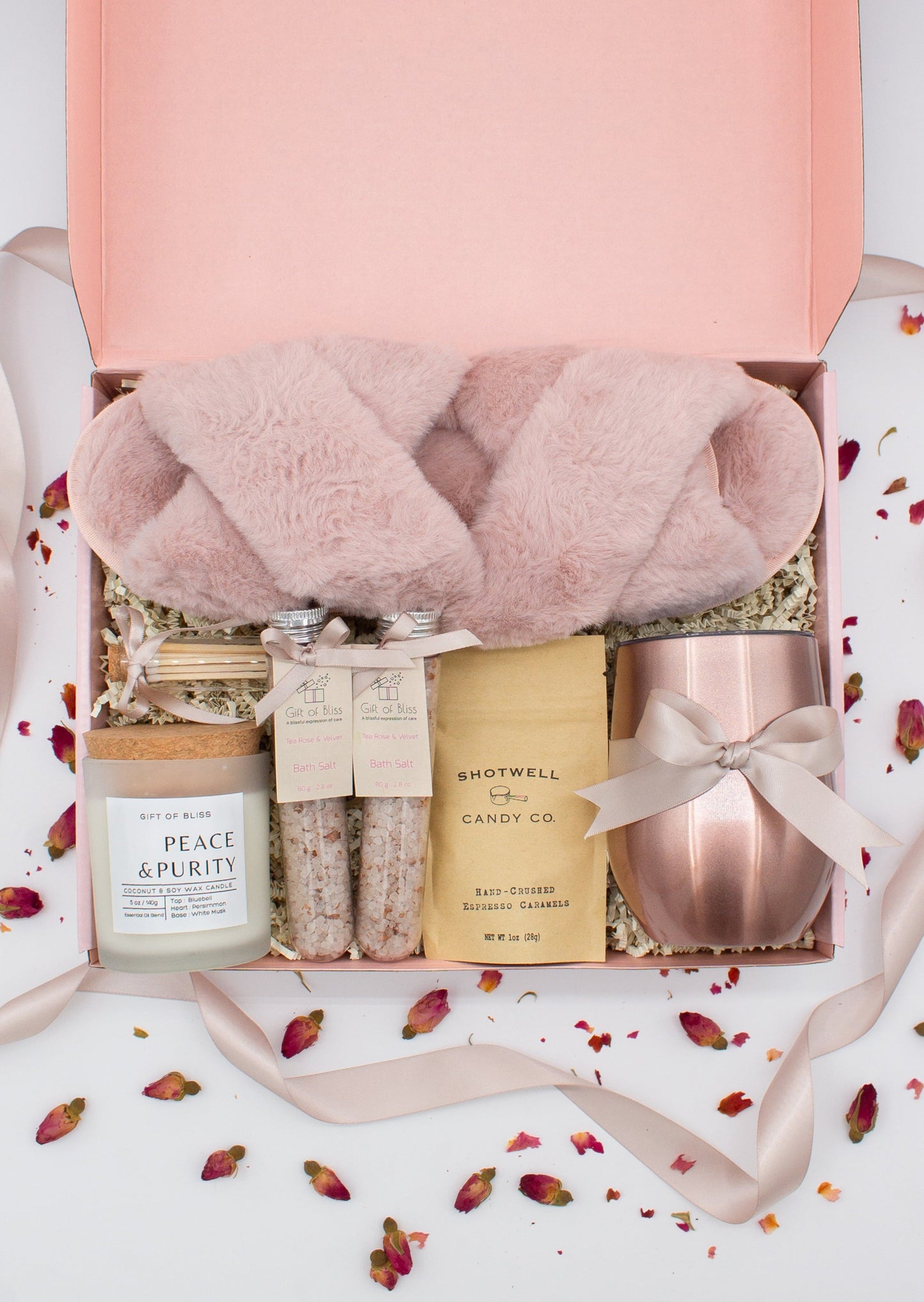 Luxury gift box for her. Featuring a stainless steel tumbler, an aromatherapy candle with matches, therapeutic bath salt, plush open-toe slippers, and gourmet caramel treats. All items are beautifully arranged for a pampering experience.