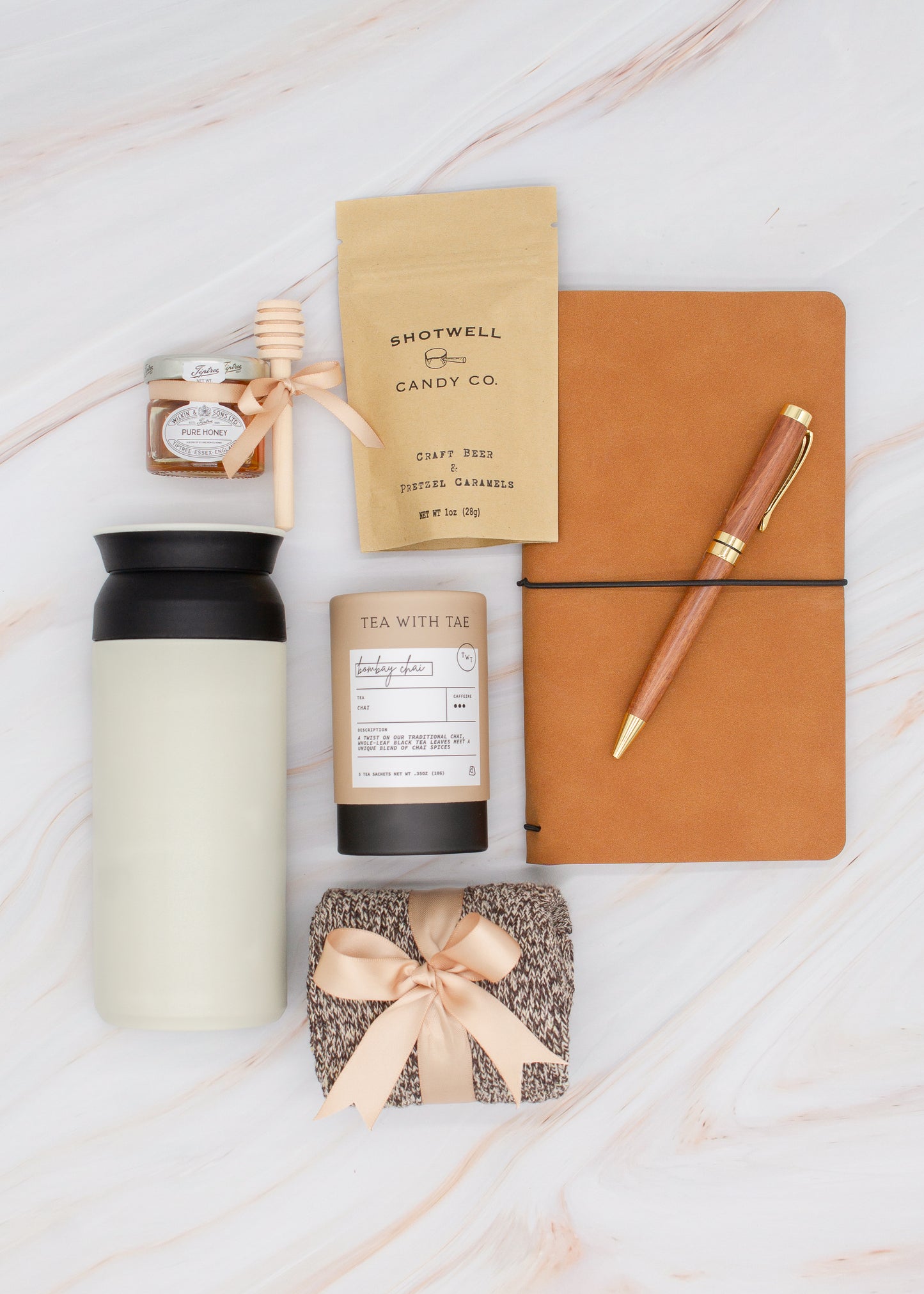 Specially crafted gift box for men, ideal for anyone. Includes a stainless steel tumbler, tea, honey, sweet treats, cozy socks, vegan leather notebook, & wooden pen. Perfect for relaxation & appreciation, complete with a personalized greeting card.