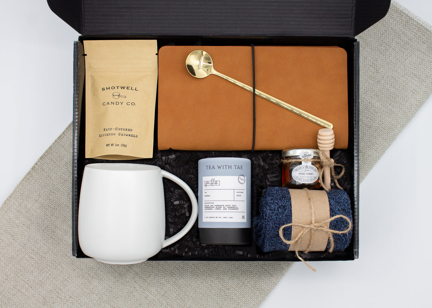 The Dapper Haven (Specially crafted gift box for men. Includes a ceramic mug, golden spoon, tea, honey with dipper, caramel candy, men's socks, and a vegan leather notebook. A gift that brings joy and a touch of tranquility to anyone who loves life's finer things.)