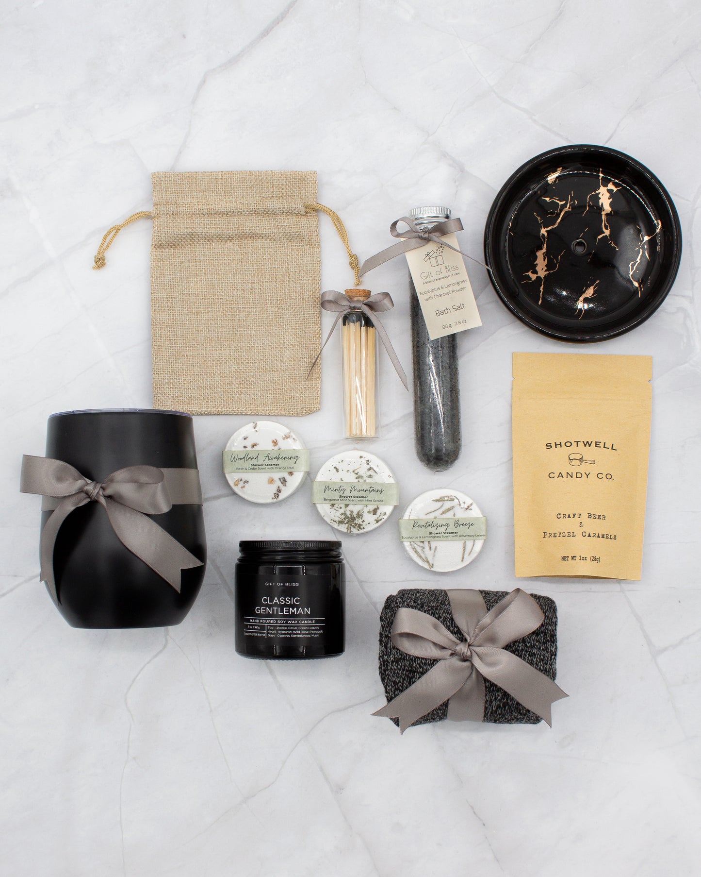 Specially crafted gift box that brings luxury and relaxation. Includes a 12oz stainless steel tumbler, sweet treats, an aromatic candle and matches, cozy socks, bath salt, shower steamers, and an elegant ceramic dish for a serene experience.