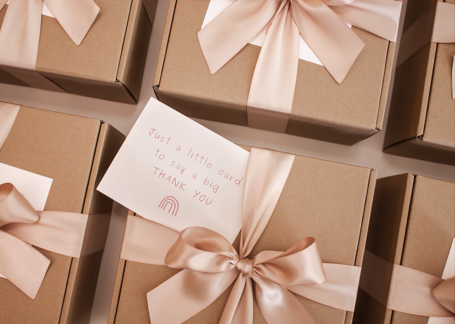 Brown gift boxes with ribbons and a card on a wooden surface