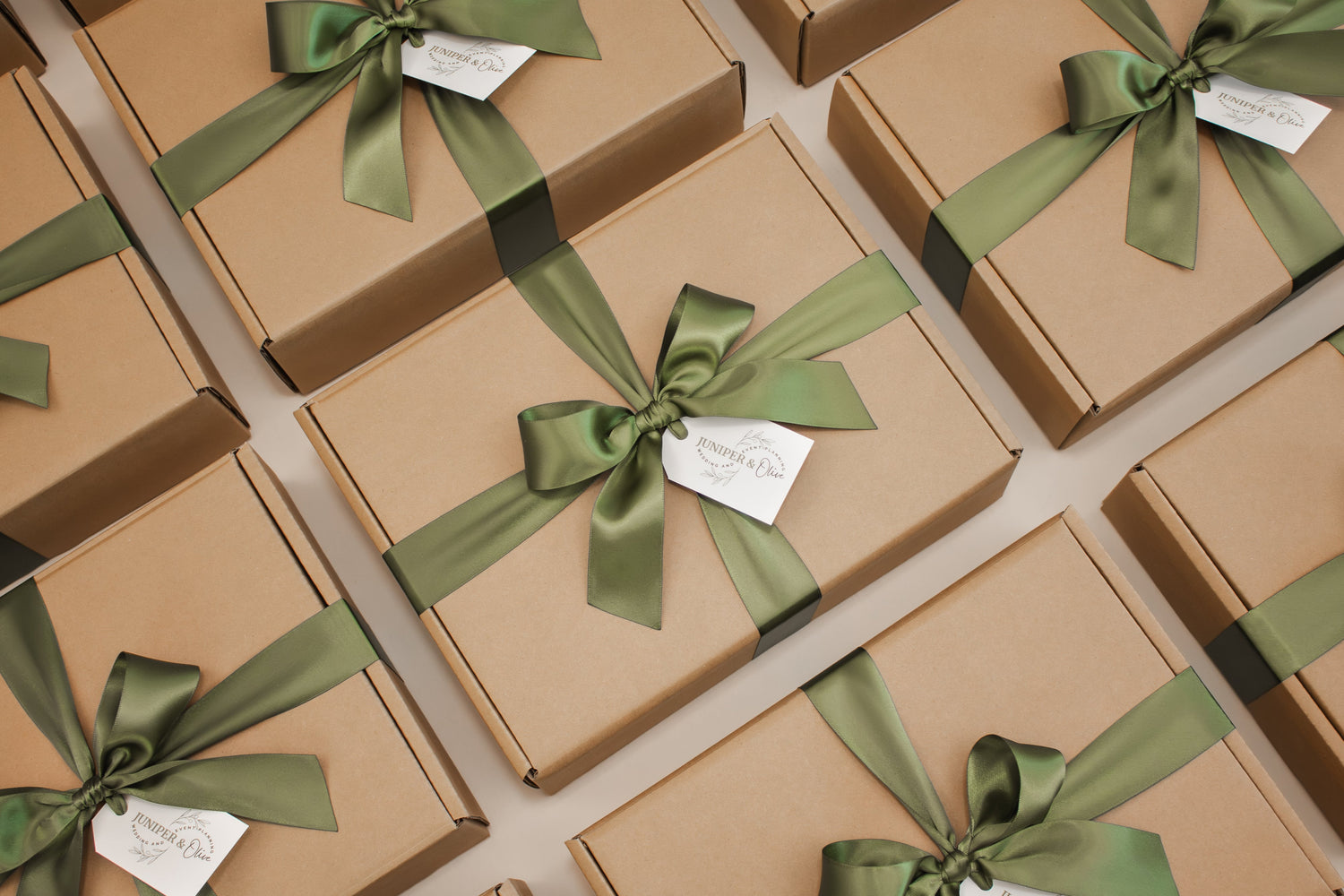 Brown gift boxes with green ribbons and company logo on gift tags arranged in a grid pattern.