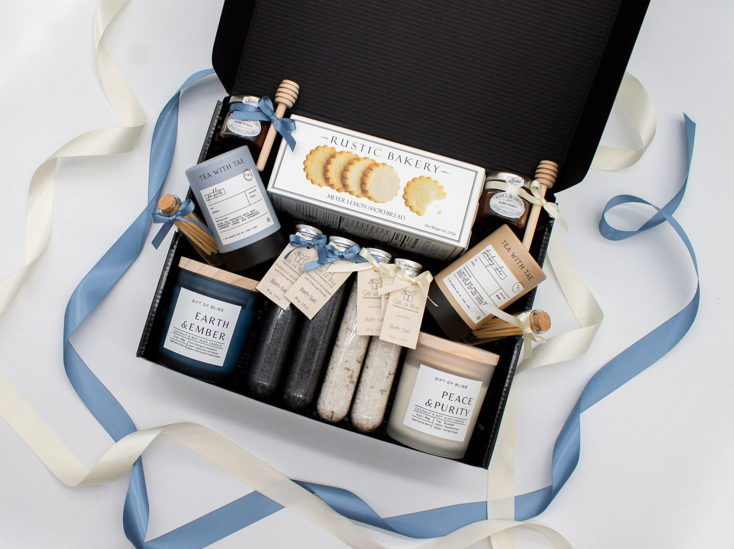 A spa gift box for two. Features shortbread cookies, 2 soothing tea blends, pure honey and wooden dipper, 2 aromatic candles, and 2 sets of bath salt. This elegantly curated box, ideal for couples, enhances shared moments of intimacy and relaxation.