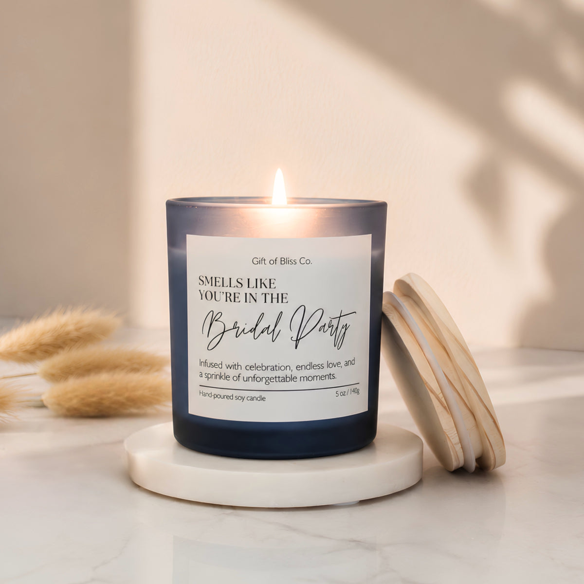 Lit Smells Like You're in the Bridal Party soy candle in a blue frosted jar with its wooden lid resting beside it