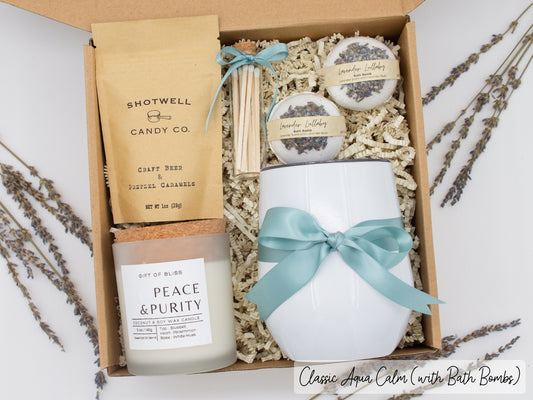 Luxury gift box for her. Featuring a stainless steel tumbler, an aromatherapy candle with matches, luxury bath bombs, and gourmet caramel treats. All items are beautifully arranged for a pampering experience.