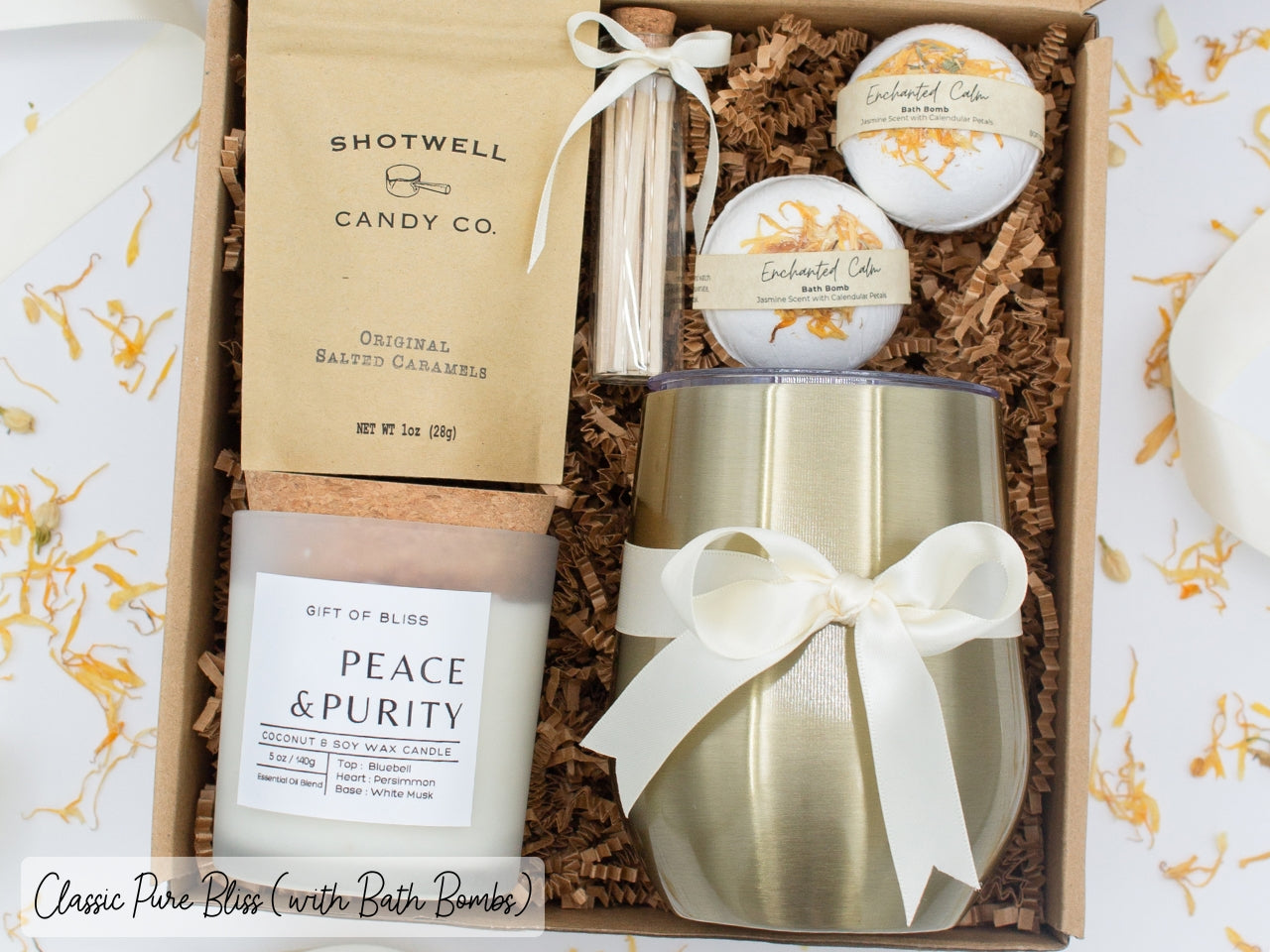 Luxury gift box for her. Featuring a stainless steel tumbler, an aromatherapy candle with matches, luxury bath bombs, and gourmet caramel treats. All items are beautifully arranged for a pampering experience.