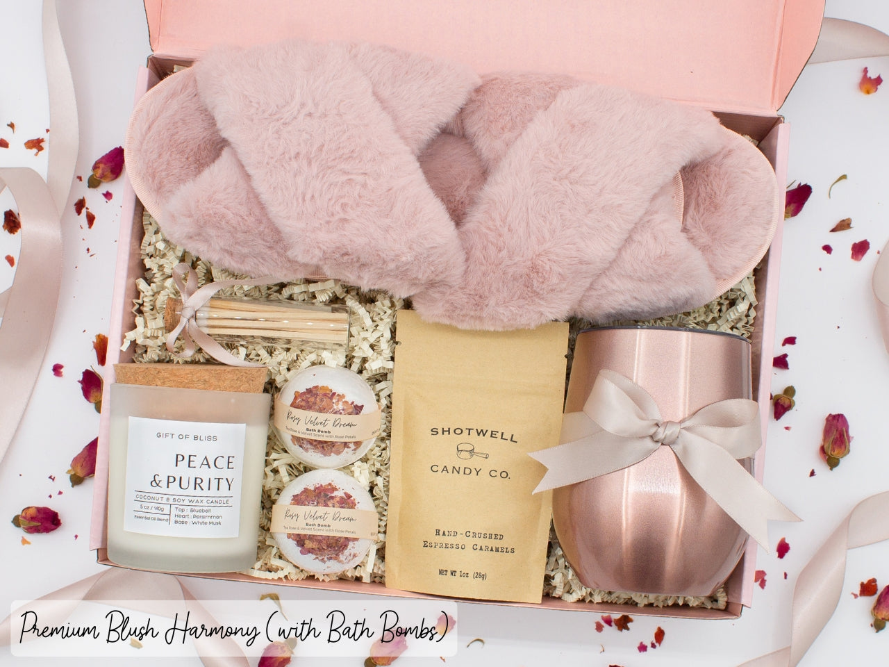 Luxury gift box for her. Featuring a stainless steel tumbler, an aromatherapy candle with matches, luxury bath bombs, plush open-toe slippers, and gourmet caramel treats. All items are beautifully arranged for a pampering experience.