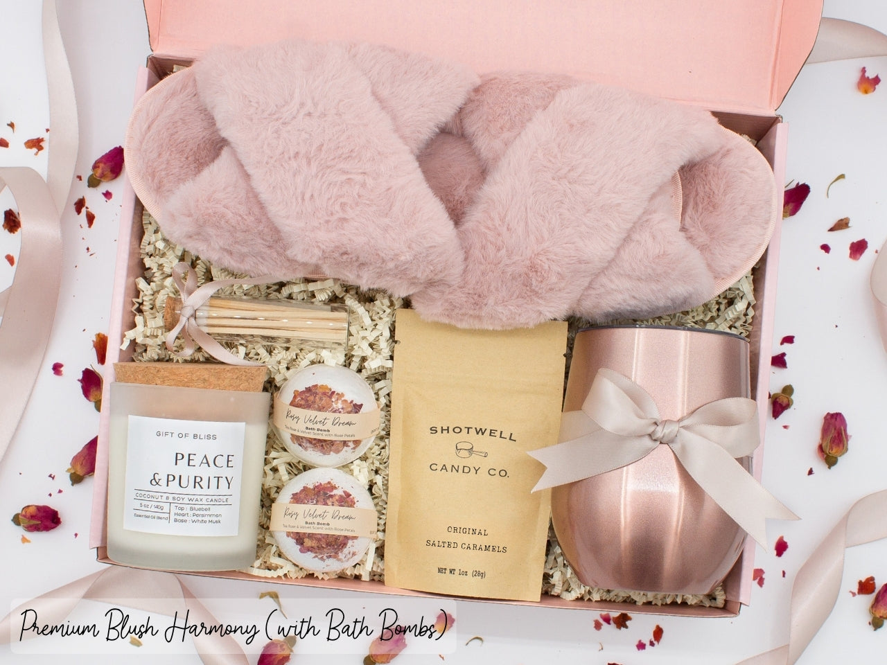 Luxury gift box for her. Featuring a stainless steel tumbler, an aromatherapy candle with matches, luxury bath bombs, plush open-toe slippers, and gourmet caramel treats. All items are beautifully arranged for a pampering experience.