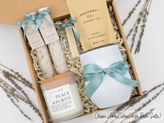 Luxury gift box for her. Featuring a stainless steel tumbler, an aromatherapy candle with matches, therapeutic bath salts, and gourmet caramel treats. All items are beautifully arranged for a pampering experience.a