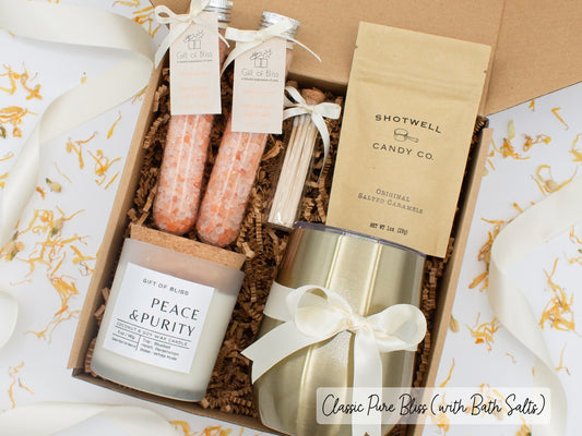 Luxury gift box for her. Featuring a stainless steel tumbler, an aromatherapy candle with matches, therapeutic bath salts, and gourmet caramel treats. All items are beautifully arranged for a pampering experience.a