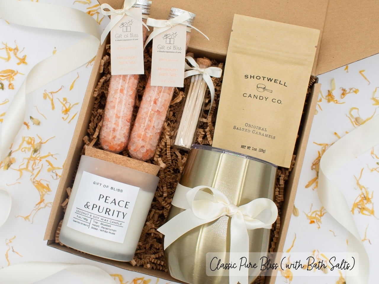 Luxury gift box for her. Featuring a stainless steel tumbler, an aromatherapy candle with matches, therapeutic bath salts, and gourmet caramel treats. All items are beautifully arranged for a pampering experience.a