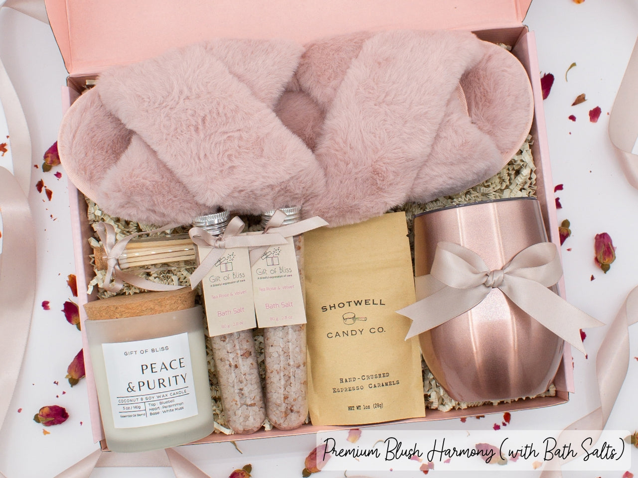 Luxury gift box for her. Featuring a stainless steel tumbler, an aromatherapy candle with matches, therapeutic bath salts, plush open-toe slippers, and gourmet caramel treats. All items are beautifully arranged for a pampering experience.