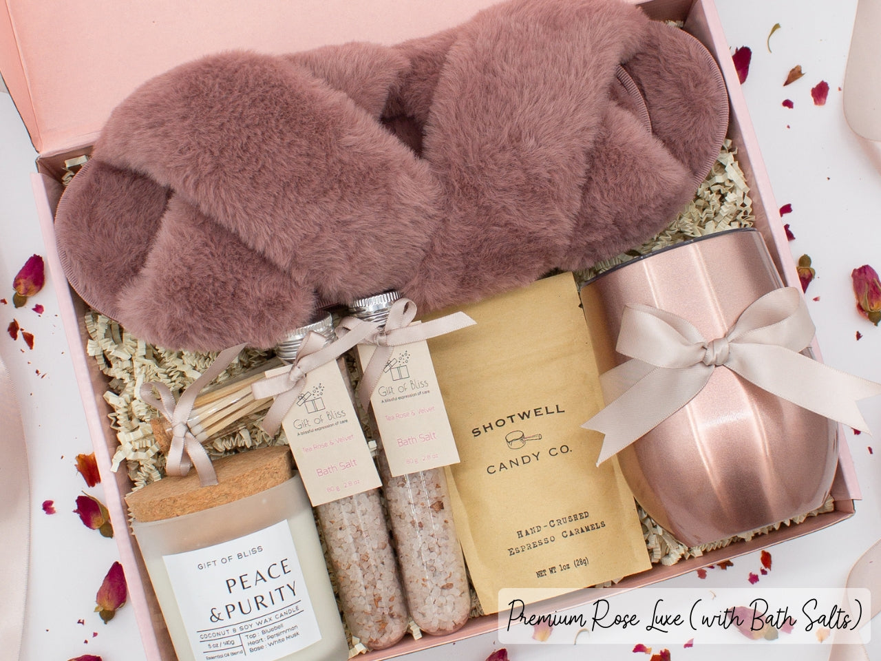 Luxury gift box for her. Featuring a stainless steel tumbler, an aromatherapy candle with matches, therapeutic bath salts, plush open-toe slippers, and gourmet caramel treats. All items are beautifully arranged for a pampering experience.