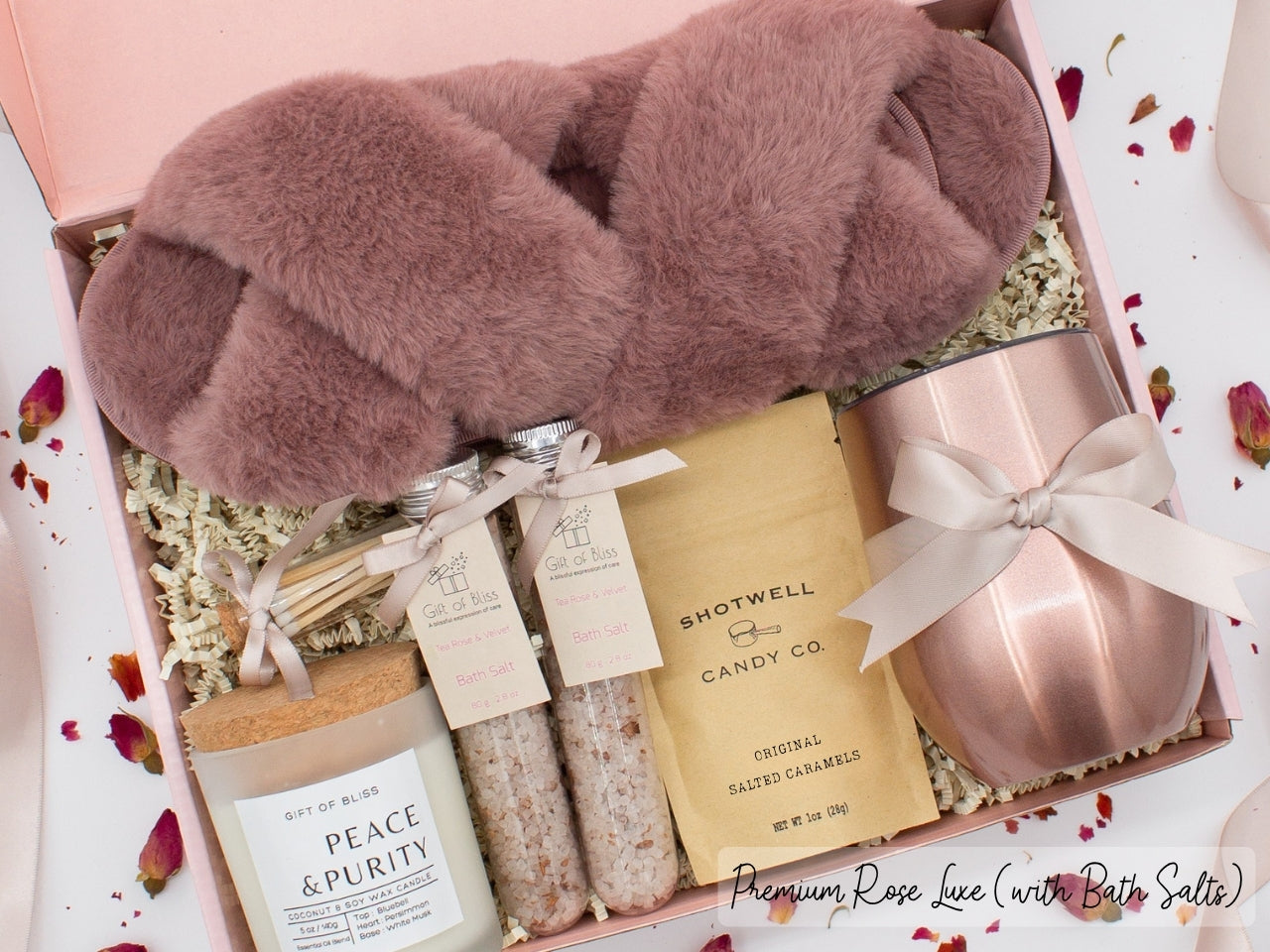 Luxury gift box for her. Featuring a stainless steel tumbler, an aromatherapy candle with matches, therapeutic bath salts, plush open-toe slippers, and gourmet caramel treats. All items are beautifully arranged for a pampering experience.