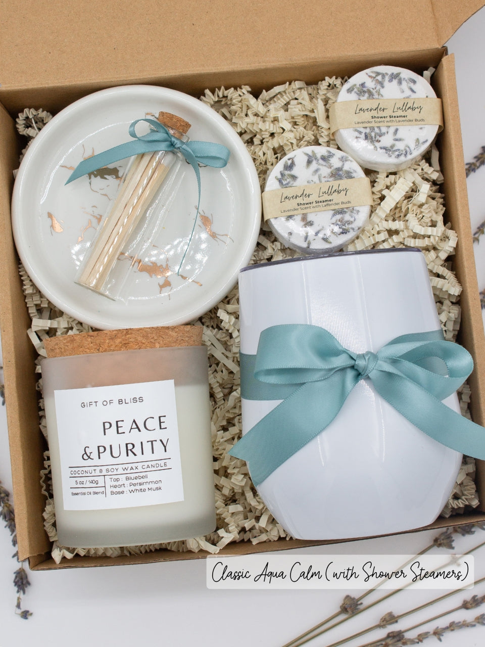 Luxury gift box for her. Featuring a stainless steel tumbler, an aromatherapy candle with matches, aromatic shower steamers, and a sleek ceramic dish. All items are beautifully arranged for a pampering experience.