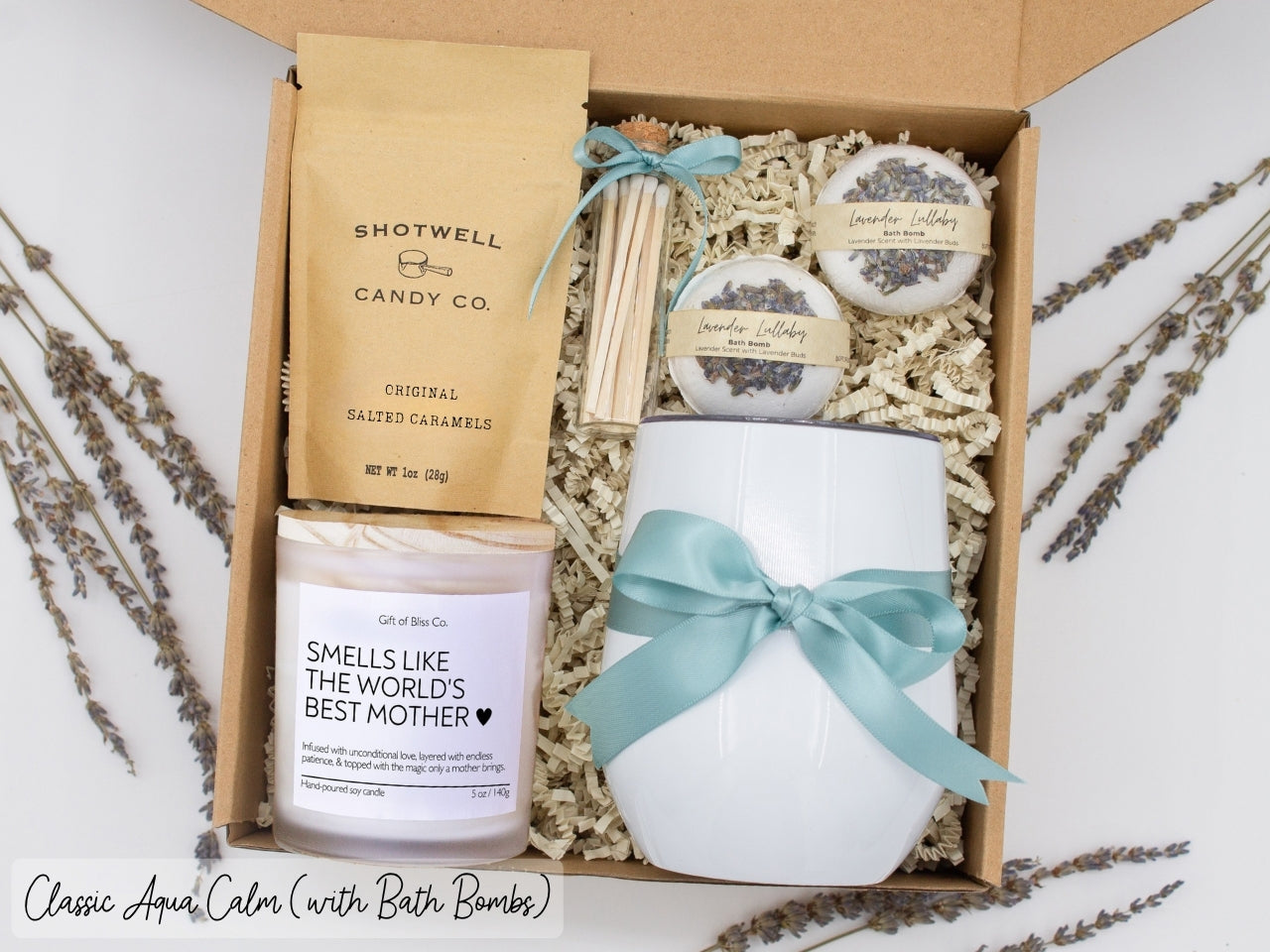 Luxury gift box for mom. Featuring a stainless steel tumbler, an aromatherapy candle with with mom-themed label and charming match jar, luxury bath bombs, and gourmet caramel treats. All items are beautifully arranged for a pampering experience.