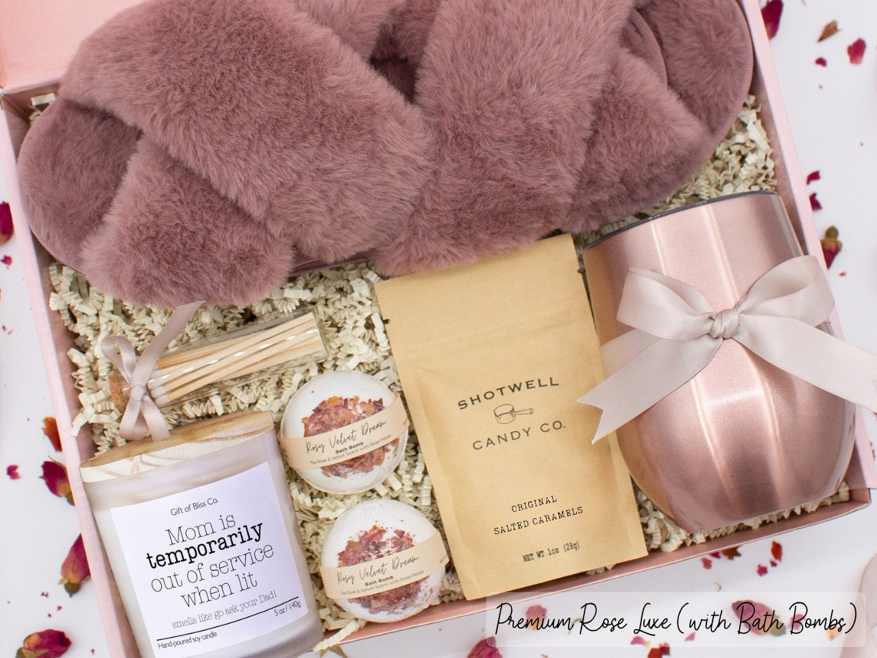 Luxury gift box for mom. Featuring a stainless steel tumbler, an aromatherapy candle with with mom-themed label and charming match jar, luxury bath bombs, plush open-toe slippers, and gourmet caramel treats. All items are beautifully arranged for a pampering experience.