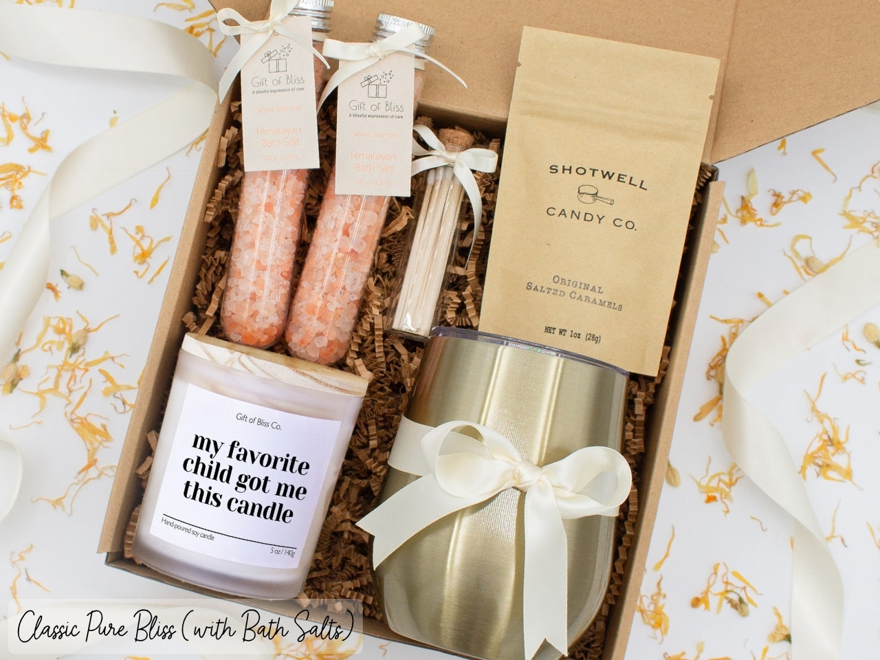 Luxury gift box for mom. Featuring a stainless steel tumbler, an aromatherapy candle with mom-themed label and charming match jar, therapeutic bath salts, and gourmet caramel treats. All items are beautifully arranged for a pampering experience.
