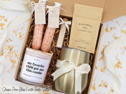 Luxury gift box for mom. Featuring a stainless steel tumbler, an aromatherapy candle with mom-themed label and charming match jar, therapeutic bath salts, and gourmet caramel treats. All items are beautifully arranged for a pampering experience.