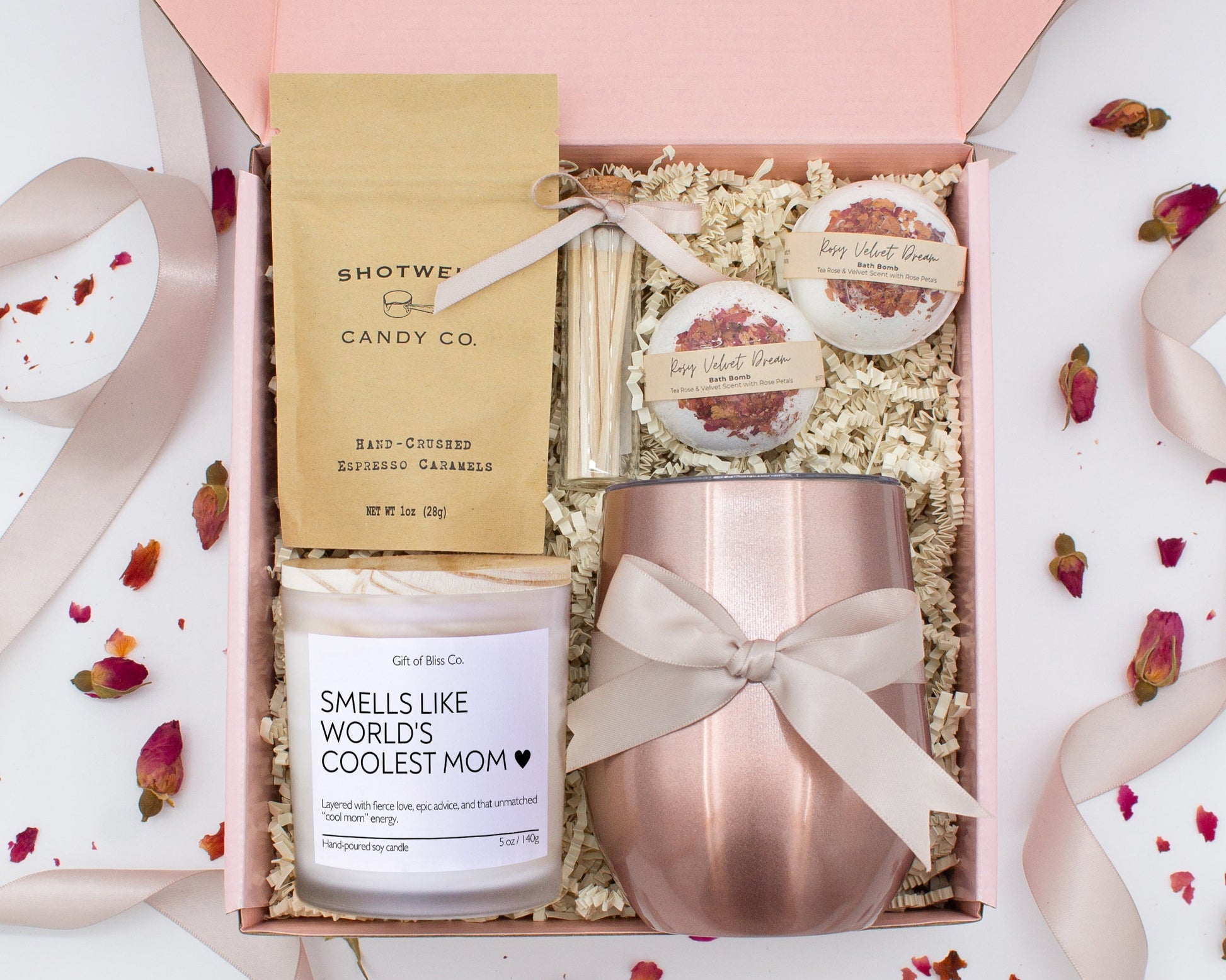 A luxury spa gift box for mom featuring a stainless steel tumbler, an aromatherapy candle with matches, therapeutic bath bombs, and gourmet caramel treats. All items are beautifully arranged for a pampering experience.
