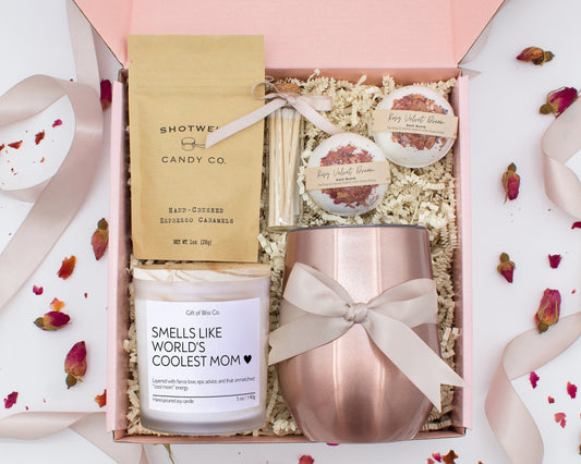A luxury spa gift box for mom featuring a stainless steel tumbler, an aromatherapy candle with matches, therapeutic bath bombs, and gourmet caramel treats. All items are beautifully arranged for a pampering experience.