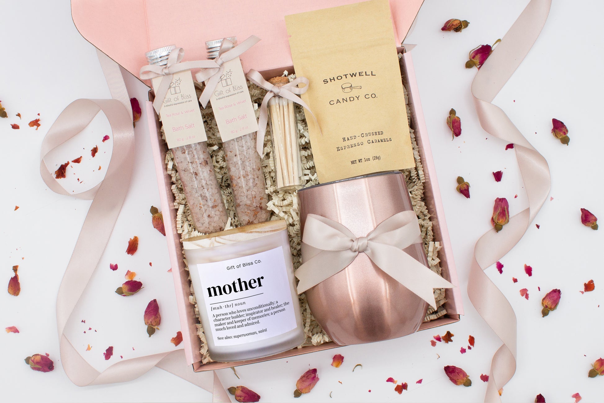 A luxury spa gift box for mom featuring a stainless steel tumbler, an aromatherapy candle with matches, therapeutic bath salt, and gourmet caramel treats. All items are beautifully arranged for a pampering experience.