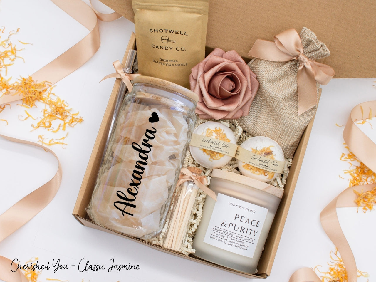 Pesonalized spa gift basket for her with fragrant bath treats, personalized glass tumbler, soft caramels, relaxing candle, and a beautifull rose. Pick from one of the three scents: Rose, Lavender, or Jasmine. Perfect to pamper and honor her.