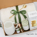 A beautifully arranged gift box for those who love home's warmth and serenity. Includes ceramic mug with golden spoon, tea tube, pure honey with wooden dipper, buttery shortbread, and soft knit blanket, all ensuring a cozy, comforting experience.