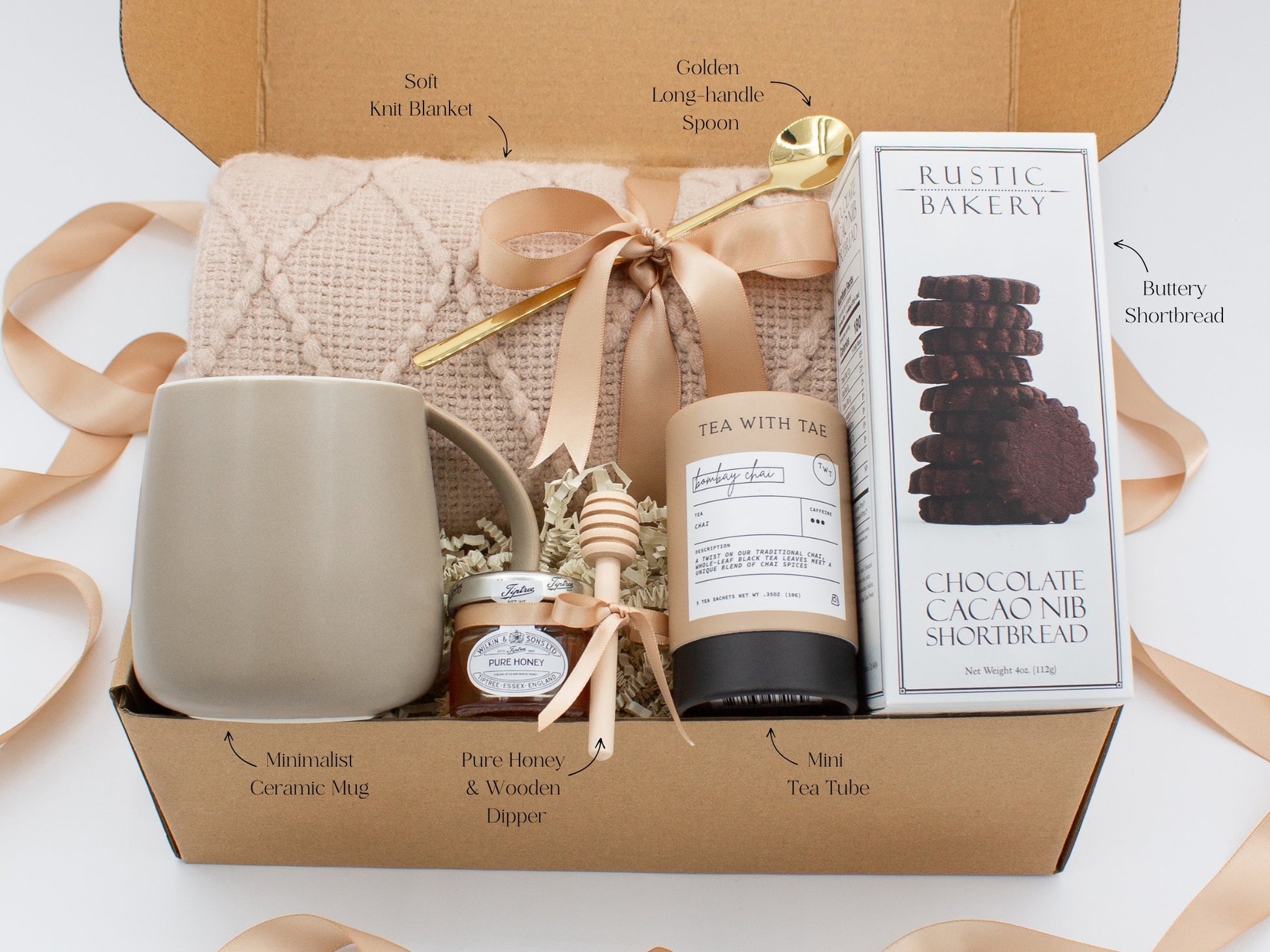 A beautifully arranged gift box for those who love home's warmth and serenity. Includes ceramic mug with golden spoon, tea tube, pure honey with wooden dipper, buttery shortbread, and soft knit blanket, all ensuring a cozy, comforting experience.