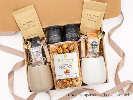 A gift box for two. Includes two ceramic mugs with golden spoons, a selection of fine coffees, two safety match jars, his and hers aromatherapy candles, caramel candies, and artisan popcorn, all for shared moments of joy.