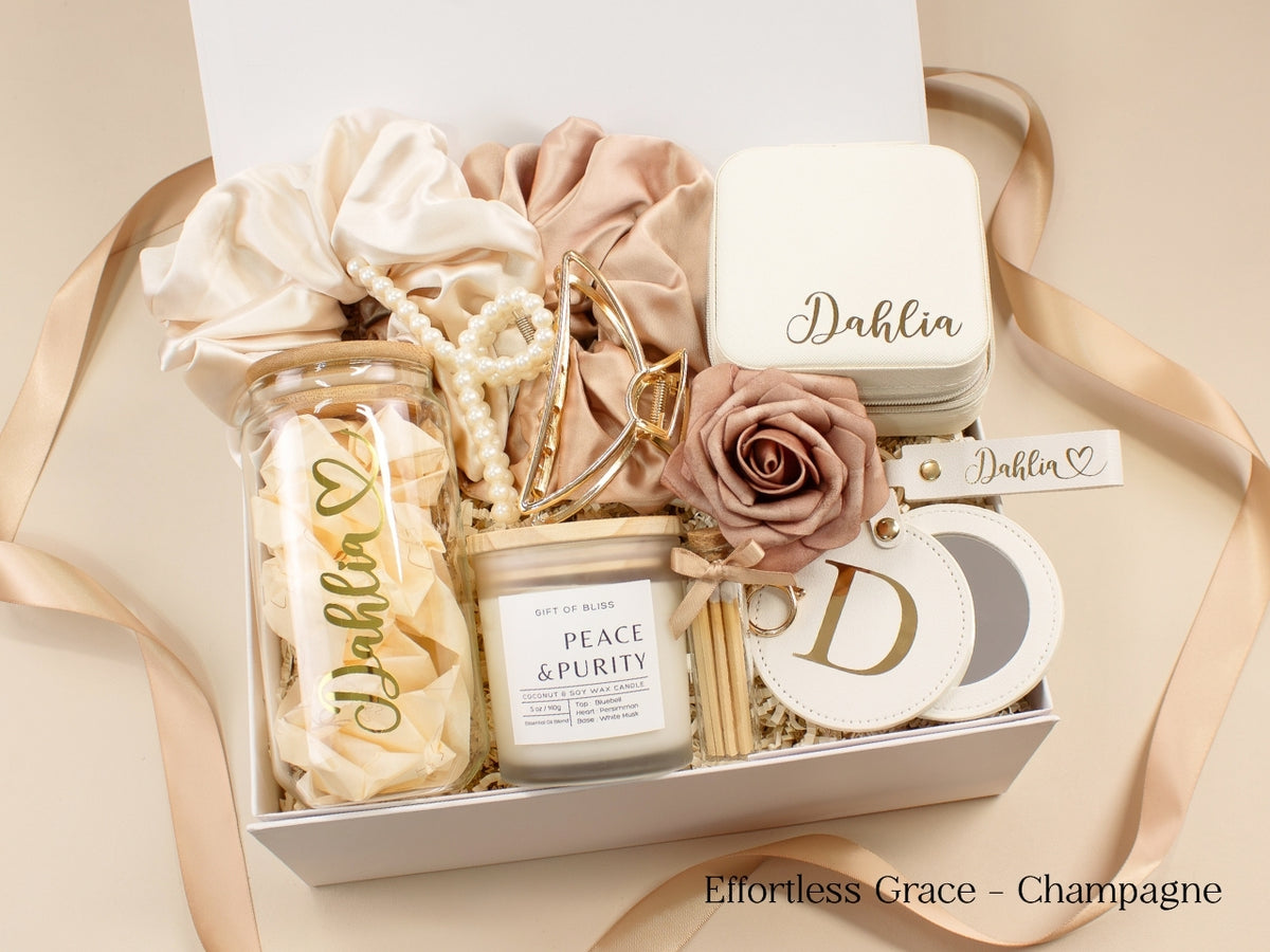 Champagne personalized gift box for her featuring glass tumbler, travel jewelry case, candle, satin scrunchies, pearl hair accessories, gold claw clip and initial mirror.