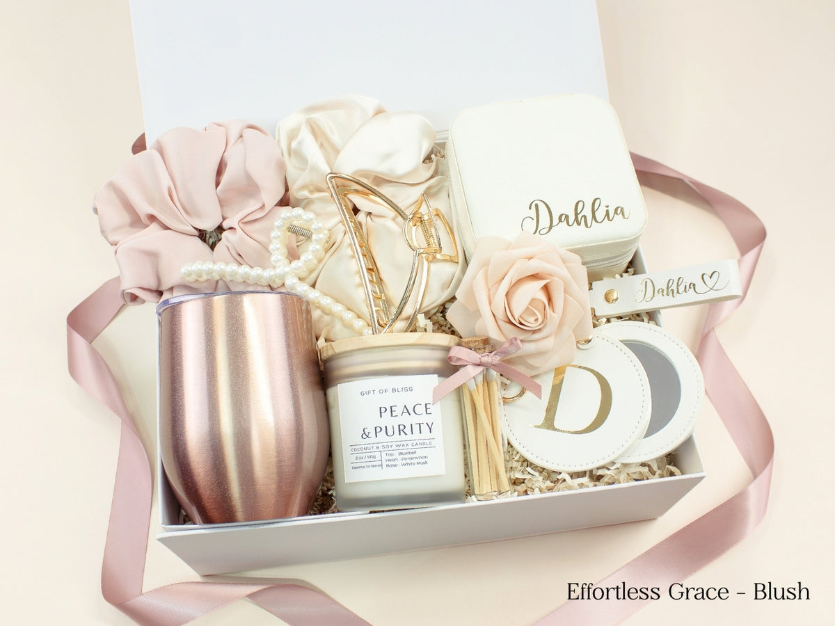 Blush pink personalized gift box for her with wine tumbler, jewelry case, candle, satin scrunchies, pearl hair accessories, gold claw clip, mirror and custom name details.