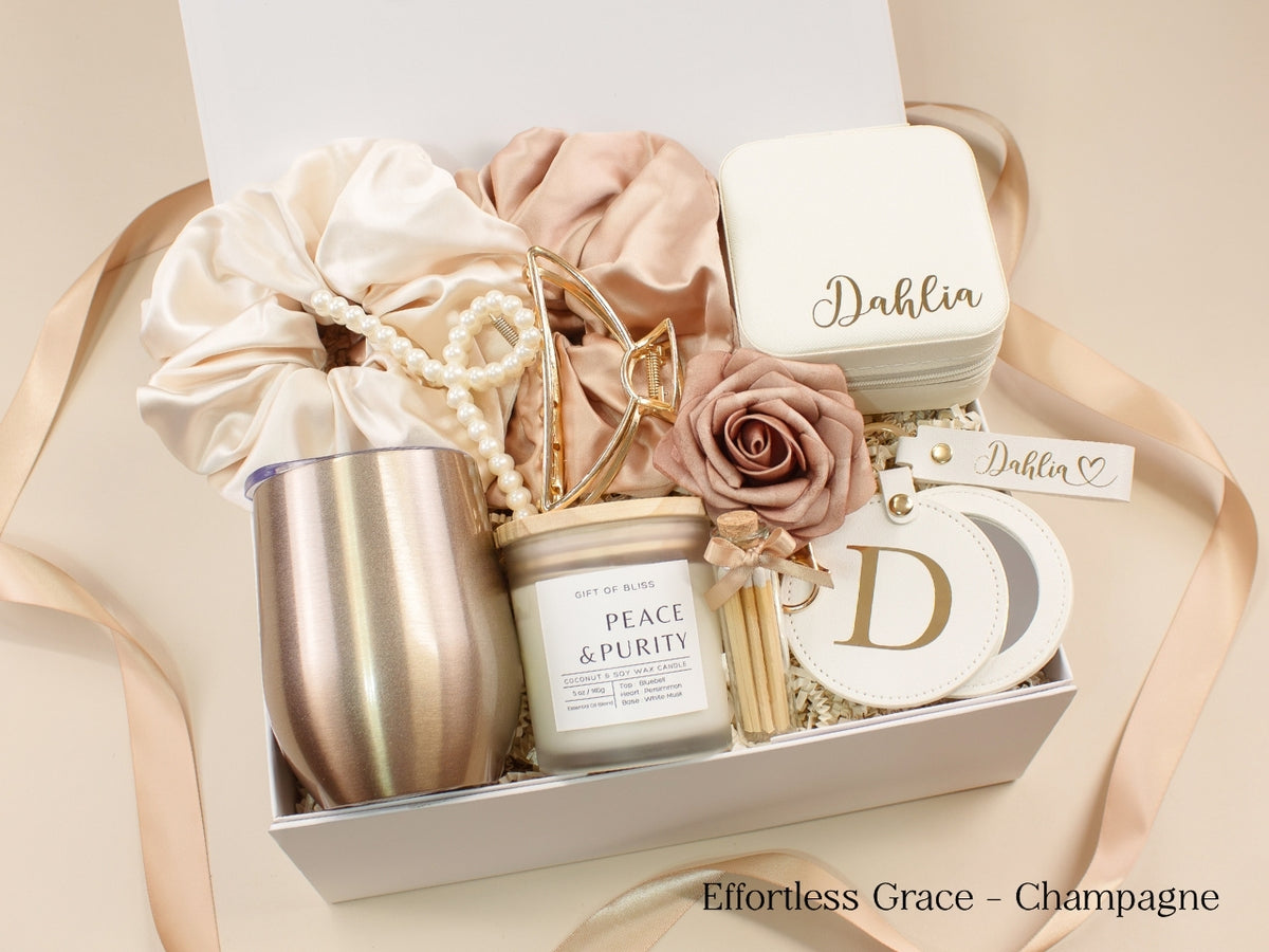 Champagne gift box for her showing personalized jewelry case, wine tumbler, candle, satin scrunchies, pearl and gold hair accessories, mirror and custom name keychain.