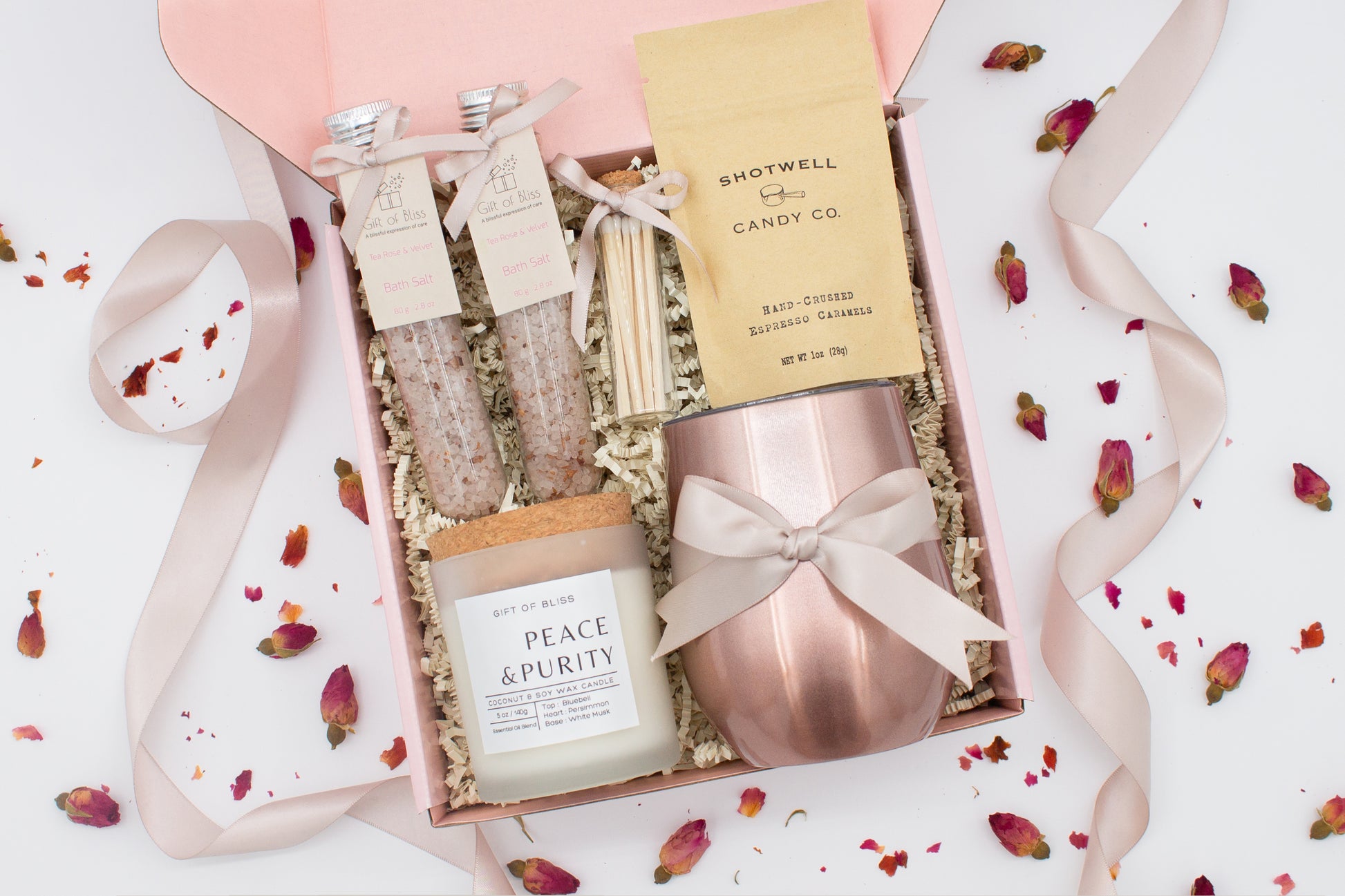 Luxury gift box for her. Featuring a stainless steel tumbler, an aromatherapy candle with matches, therapeutic bath salt, and gourmet caramel treats. All items are beautifully arranged for a pampering experience.