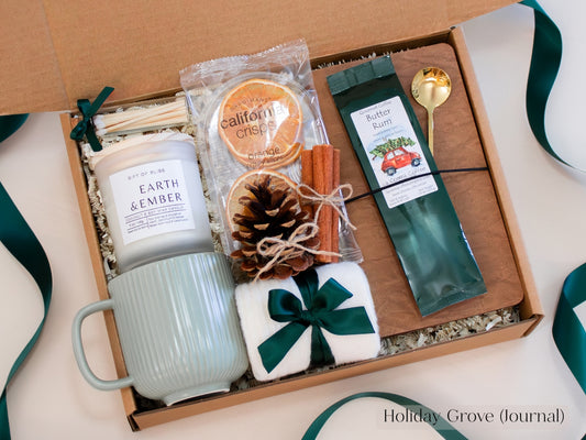 Spruce-green Christmas gift box for him with ribbed ceramic mug, Earth & Ember candle, butter rum coffee, dried oranges, pinecone, cinnamon sticks, journal, and gold spoon - an earthy and comforting holiday gift set tied with forest-green ribbon.