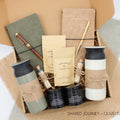 A gift box for two, features two stainless steel tumblers, two notebooks with a gold pen and a wooden pen, gourmet caramels, and two aromatic candles. Perfect for couples, friends, or colleagues to enjoy a relaxing, creative experience together.