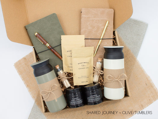 A gift box for two, features two stainless steel tumblers, two notebooks with a gold pen and a wooden pen, gourmet caramels, and two aromatic candles. Perfect for couples, friends, or colleagues to enjoy a relaxing, creative experience together.