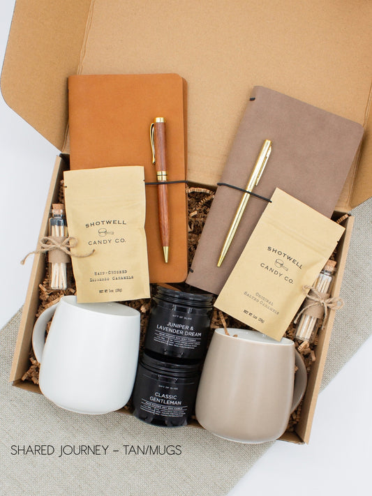 A gift box for two, features two ceramic mugs, two notebooks with a gold pen and a wooden pen, gourmet caramel candies, and two aromatic candles. Perfect for couples, friends, or colleagues to enjoy a relaxing, creative experience together.