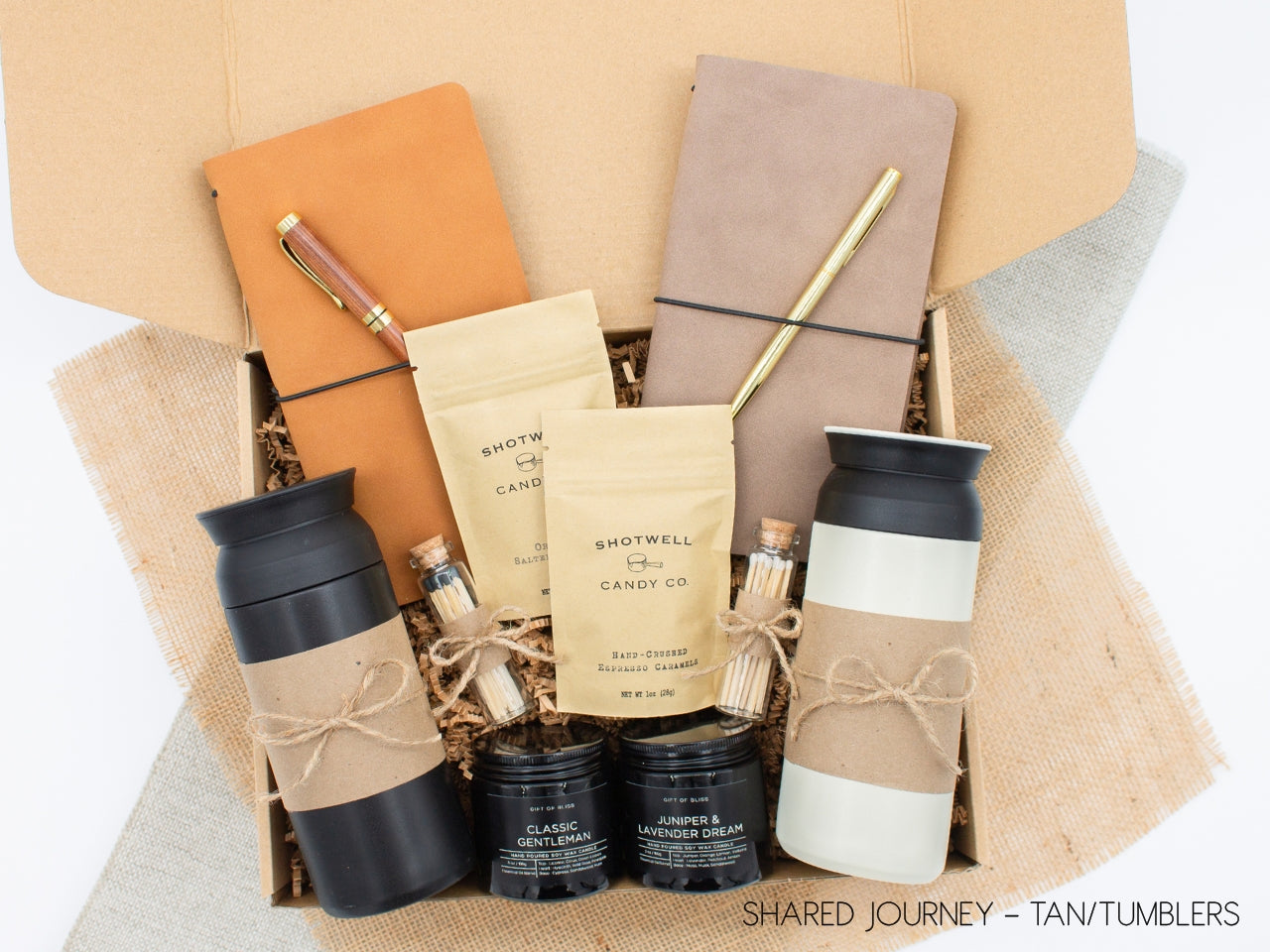 A gift box for two, features two stainless steel tumblers, two notebooks with a gold pen and a wooden pen, gourmet caramels, and two aromatic candles. Perfect for couples, friends, or colleagues to enjoy a relaxing, creative experience together.