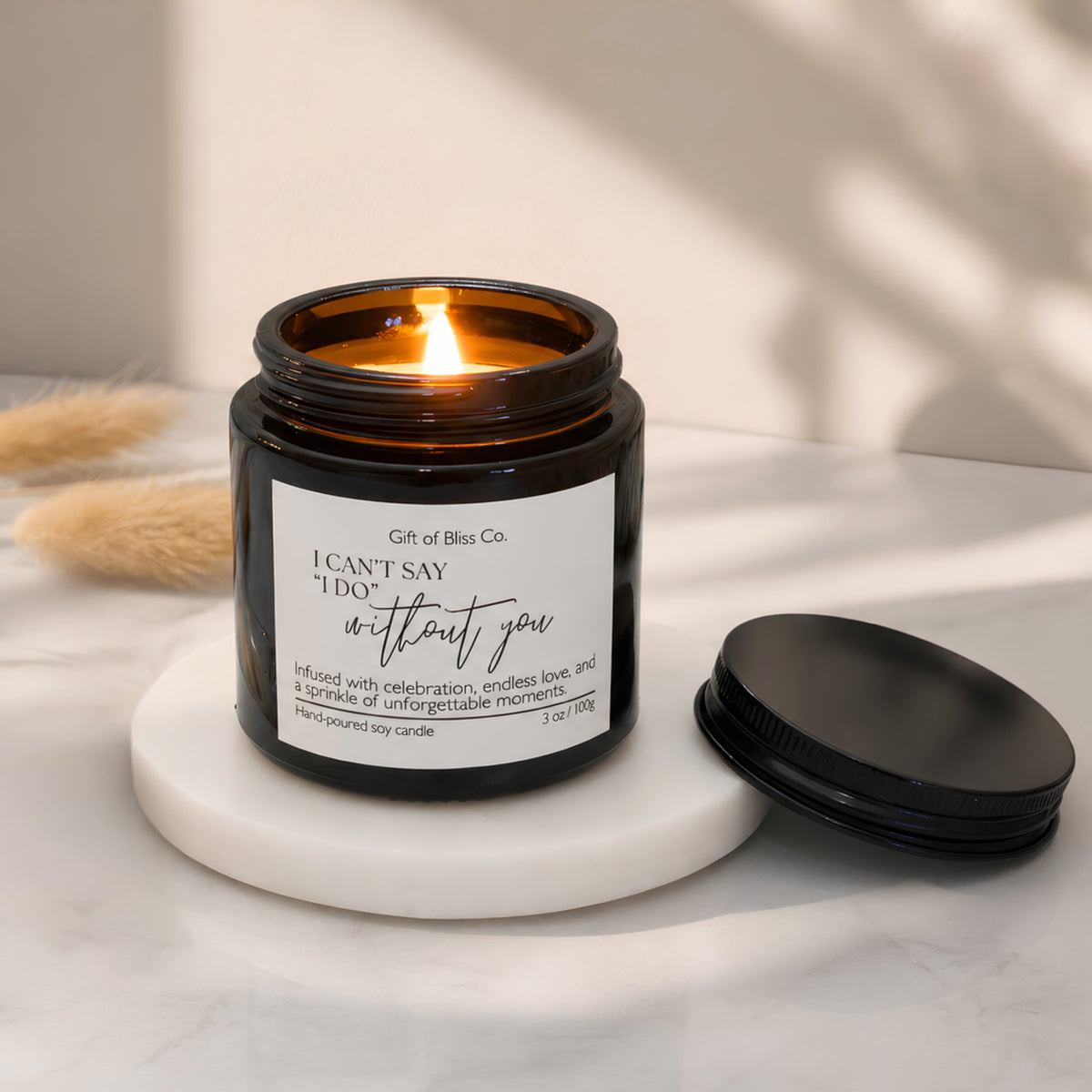 Lit I Can't Say I Do Without You soy candle in a 3 oz black jar with its metal lid resting beside it