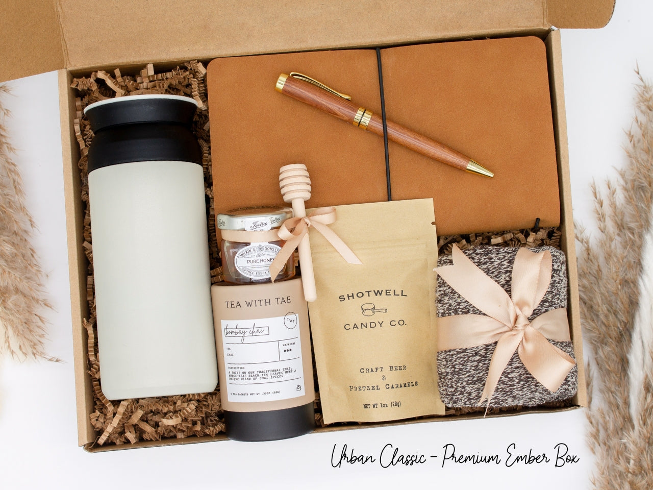 Specially crafted gift box for men, ideal for anyone. Includes a stainless steel tumbler, tea, honey, sweet treats, cozy socks, vegan leather notebook, & wooden pen. Perfect for relaxation & appreciation, complete with a personalized greeting card.